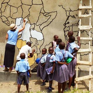 Schoolchildren in uniforms at a hand-painted wall map in Ntandi, Uganda